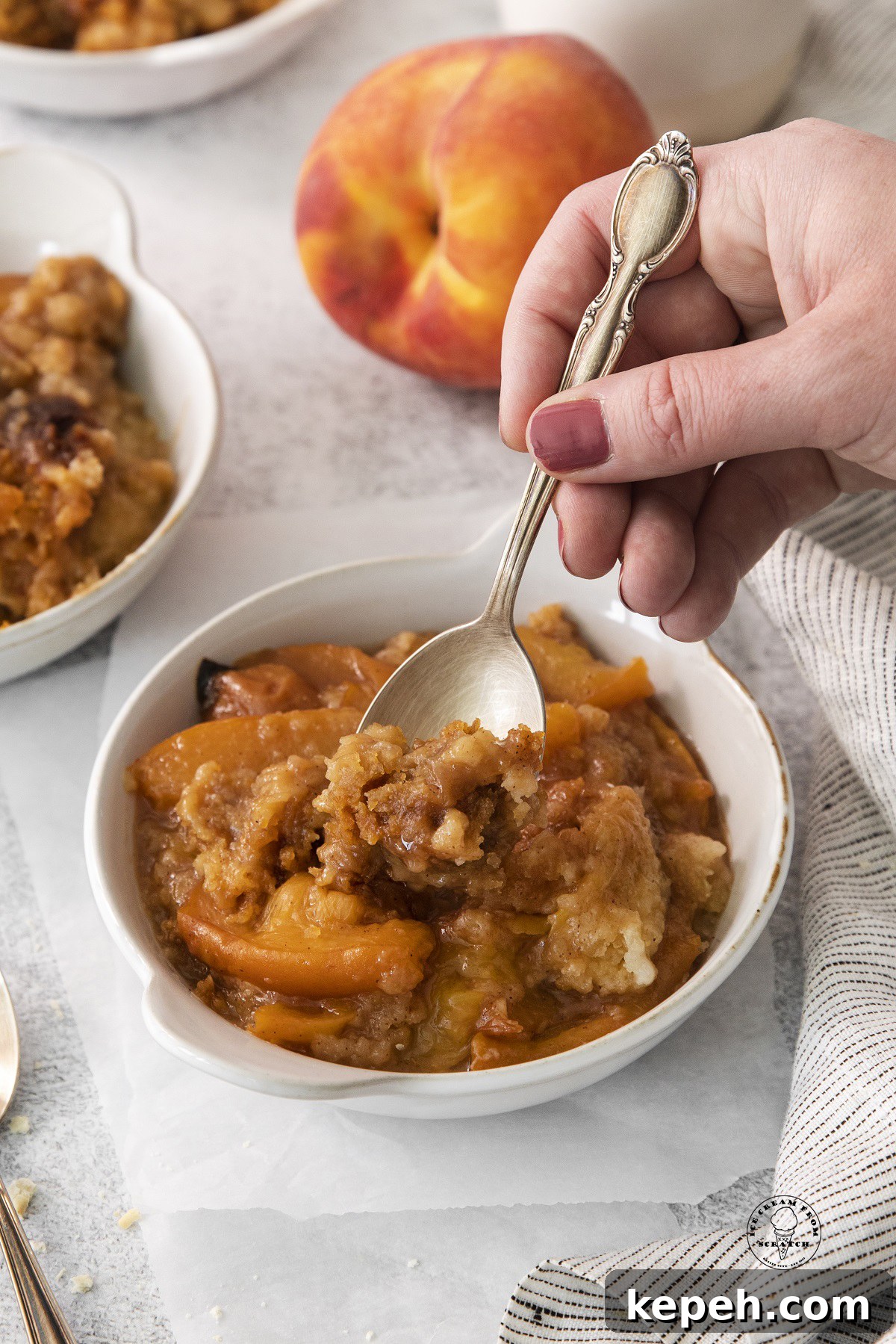 a serving of peach cobber being enjoyed with a spoon.