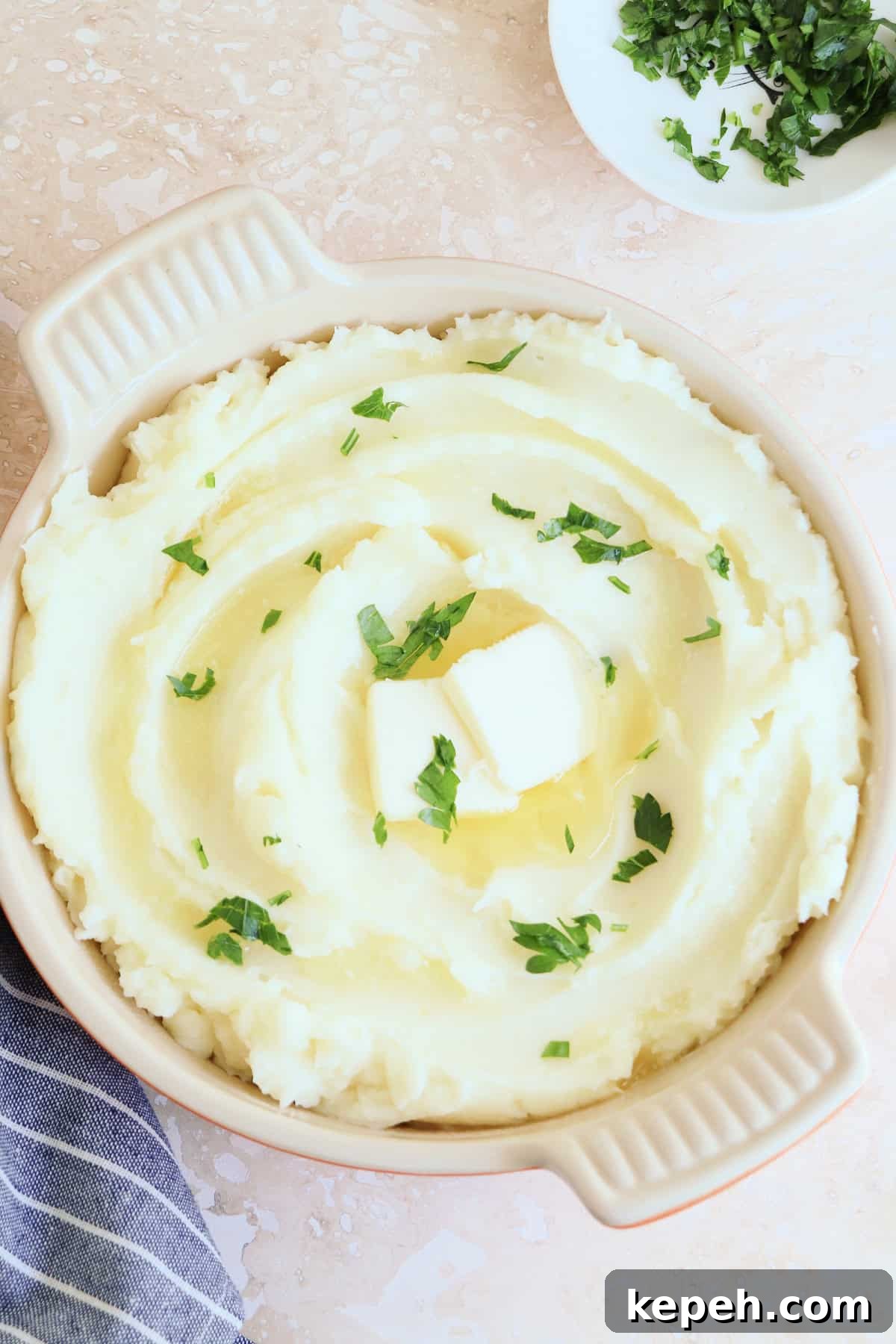 Classic Creamy Mashed Potatoes Recipe for Perfectly Smooth Results 14 Creamy and smooth mashed potatoes in a serving dish with handles, garnished with chopped parsley.