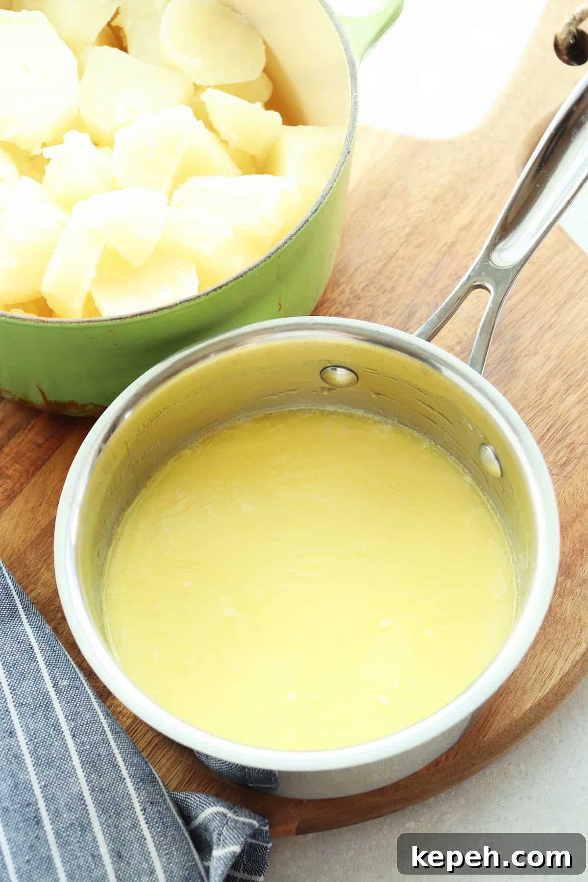 Classic Creamy Mashed Potatoes Recipe for Perfectly Smooth Results 7 Melted butter and milk in a small stainless steel saucepan, set on a wooden board.