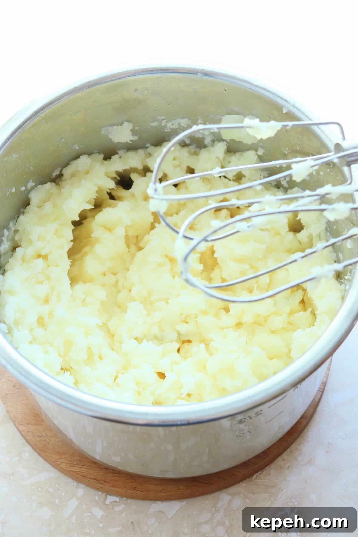 Classic Creamy Mashed Potatoes Recipe for Perfectly Smooth Results 8 Mashed potatoes in a stainless steel pot with mixer paddles on the right side.
