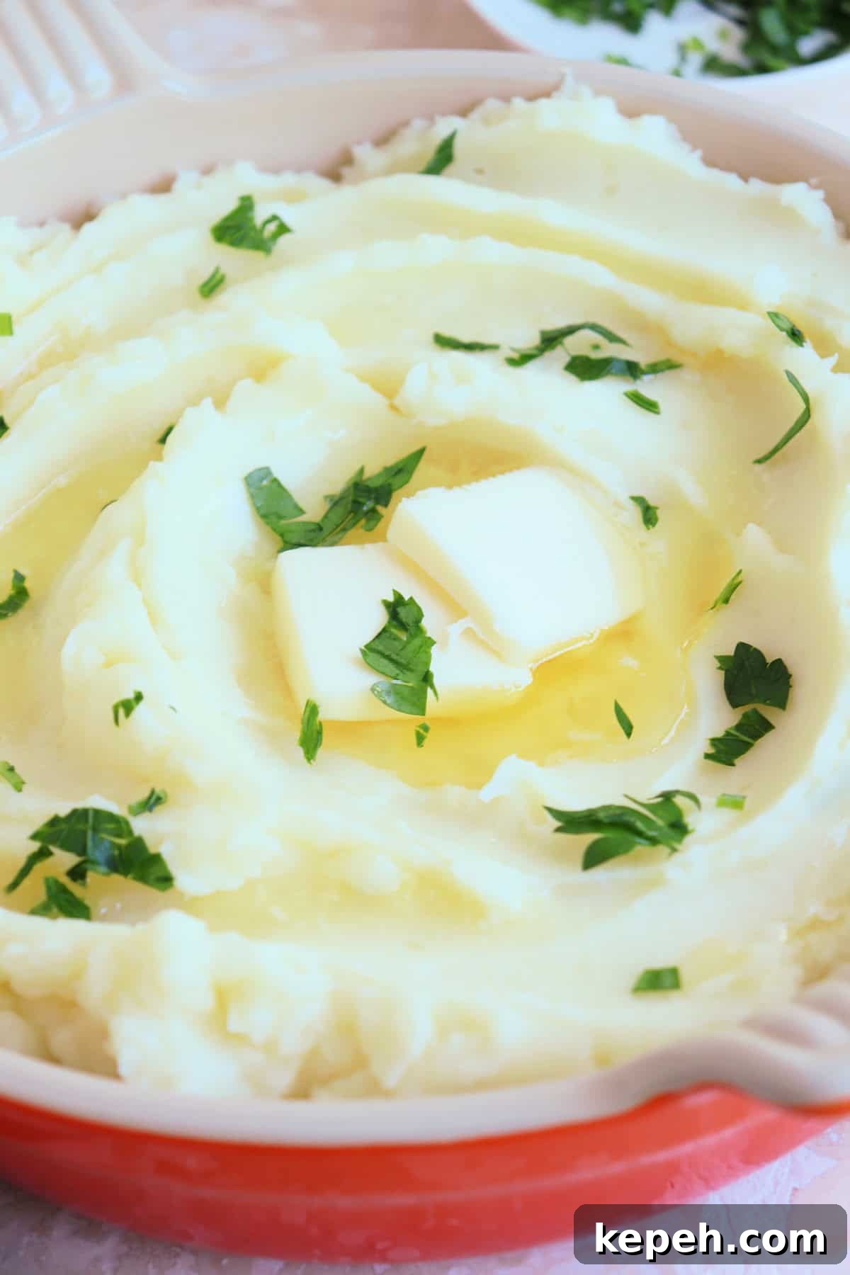 Classic Creamy Mashed Potatoes Recipe for Perfectly Smooth Results 9 Close up on creamy mashed potatoes garnished with chopped Italian parsley and drizzled with melted butter.