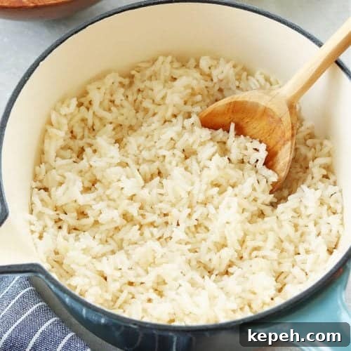 Square image of cooked long-grain rice in a blue pot on a gray board.