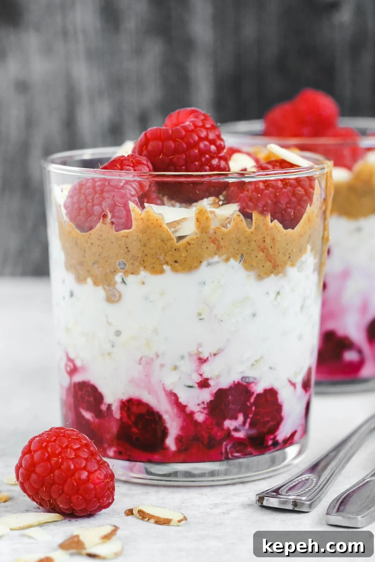 Creamy Raspberry Overnight Oats Recipe for Quick Breakfast 2 glass filled with layers of raspberries, overnight oats, and almond butter