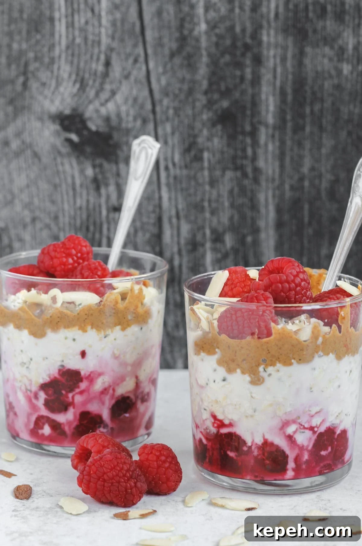 Creamy Raspberry Overnight Oats Recipe for Quick Breakfast 5 two glass cups filled with overnight oats, raspberries, almond butter, and almonds
