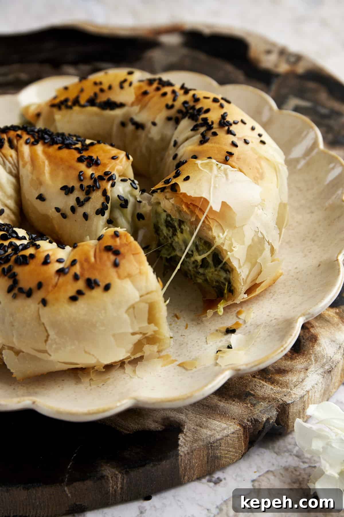 Side view of a sliced phyllo spanakopita roll exposing the cheese and spinach filling.