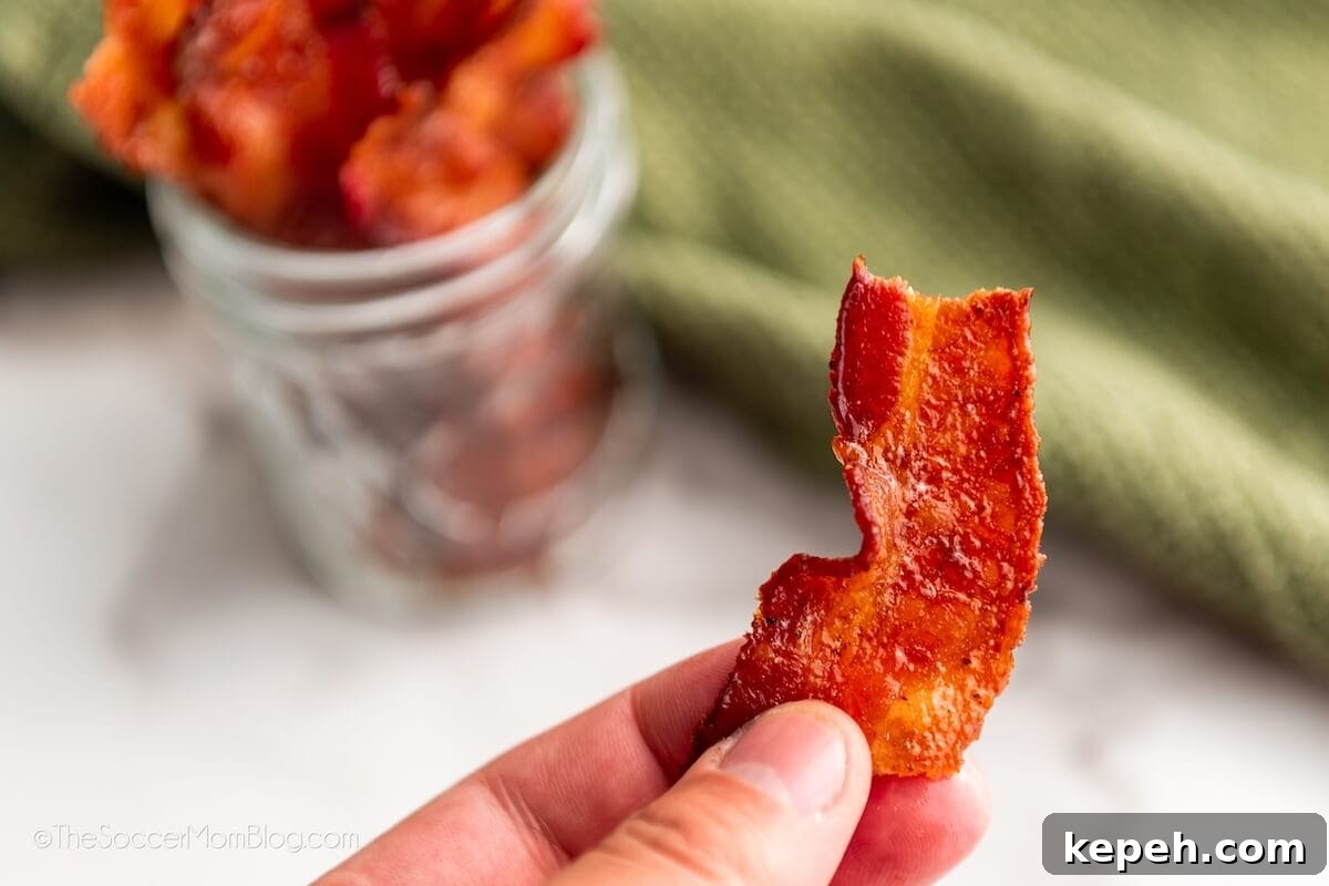 How to Make Crispy Sweet Candied Bacon at Home 3 holding a piece of "pig candy"