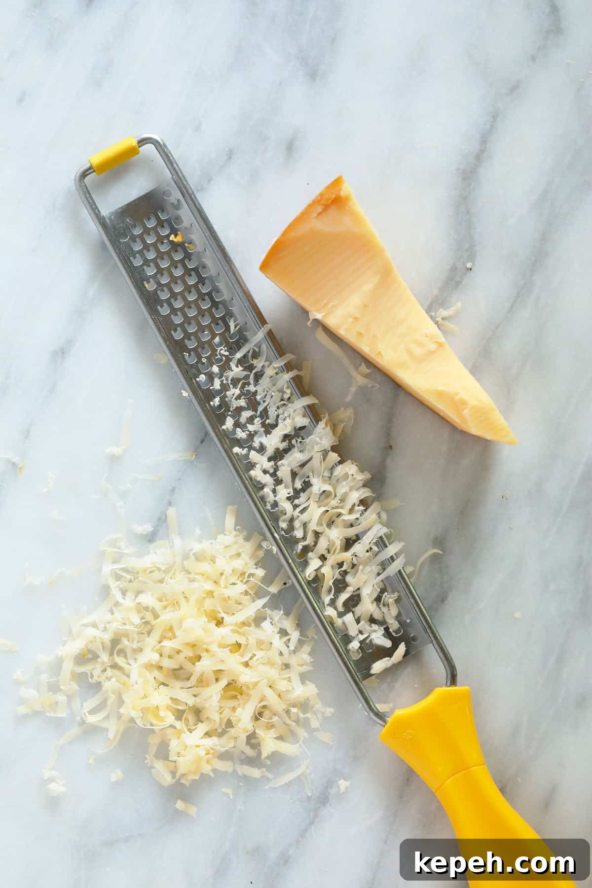 A zester and a piece of cheese on a cutting board.