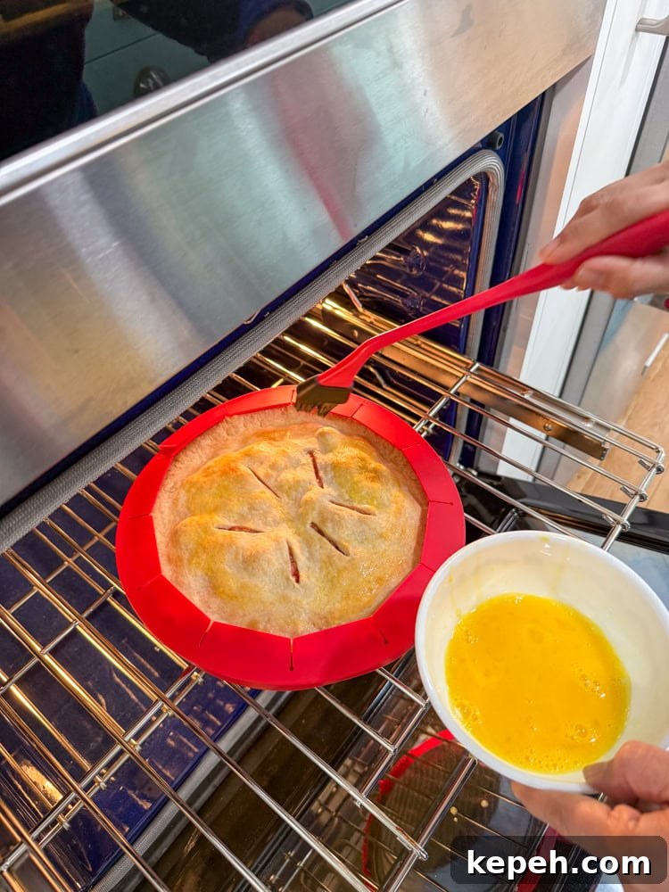 Strawberry Rhubarb Pie Recipe: Sweet-Tart Summer Dessert 13 brushing egg wash into the pie