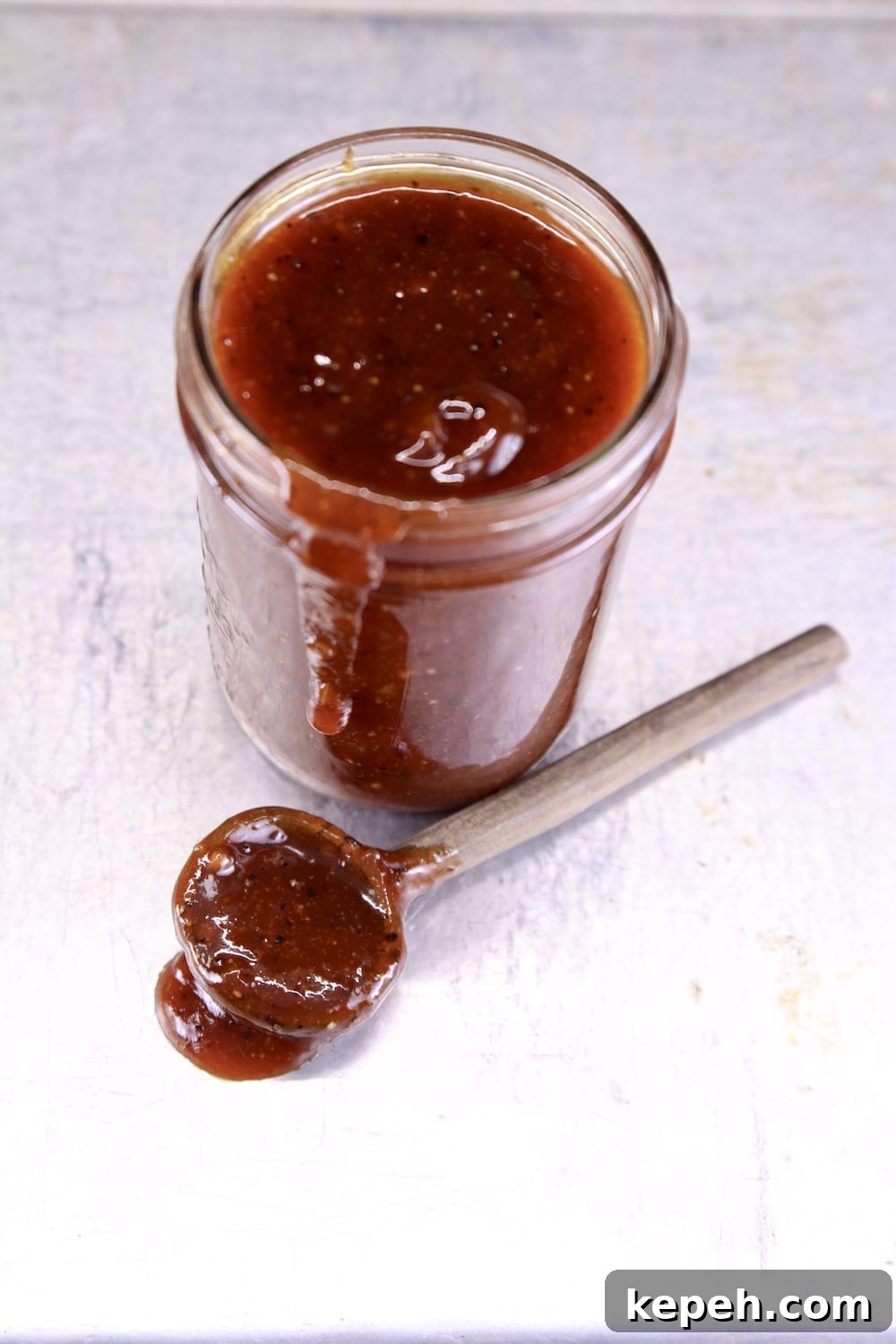 jar of bbq sauce with a spoon of sauce on the sheet pan