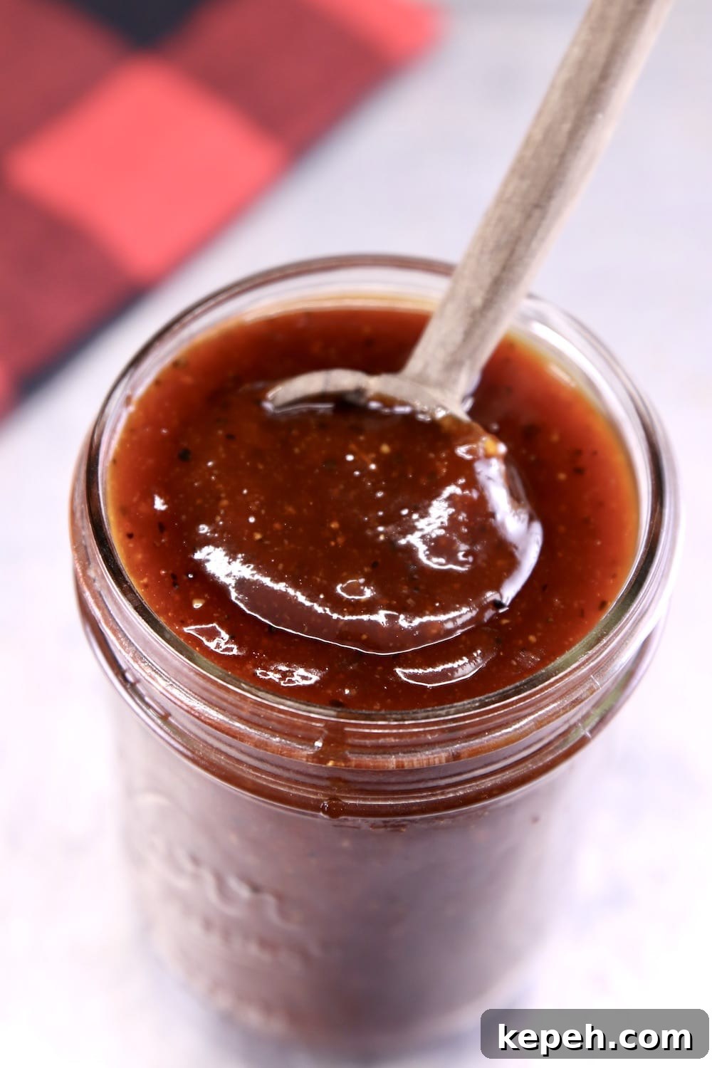Thick bbq sauce in a jar with a wood spoon