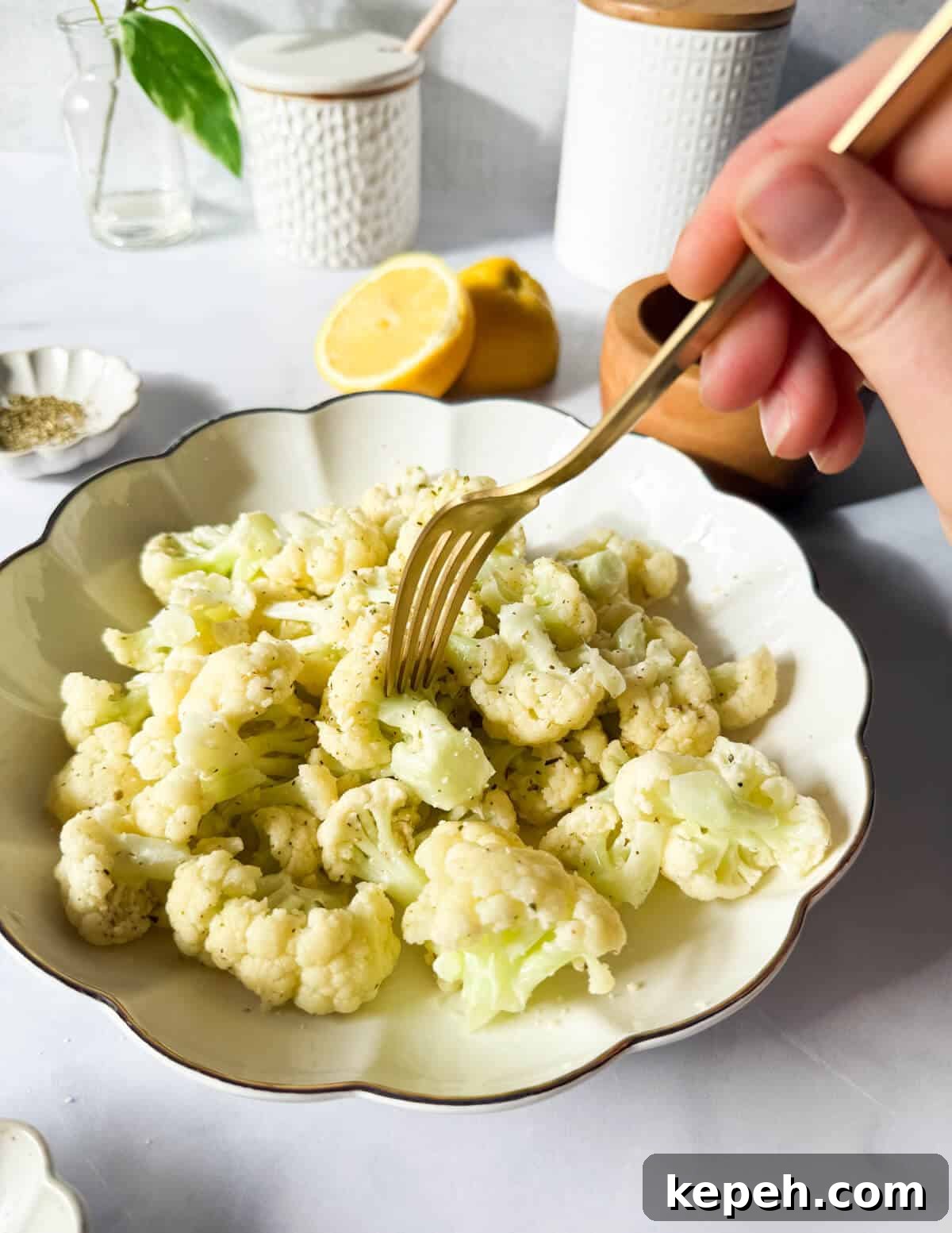 Garlic Butter Microwave Cauliflower Recipe for Quick Sides 12 a fork poking a steamed cauliflower coated in garlic butter.