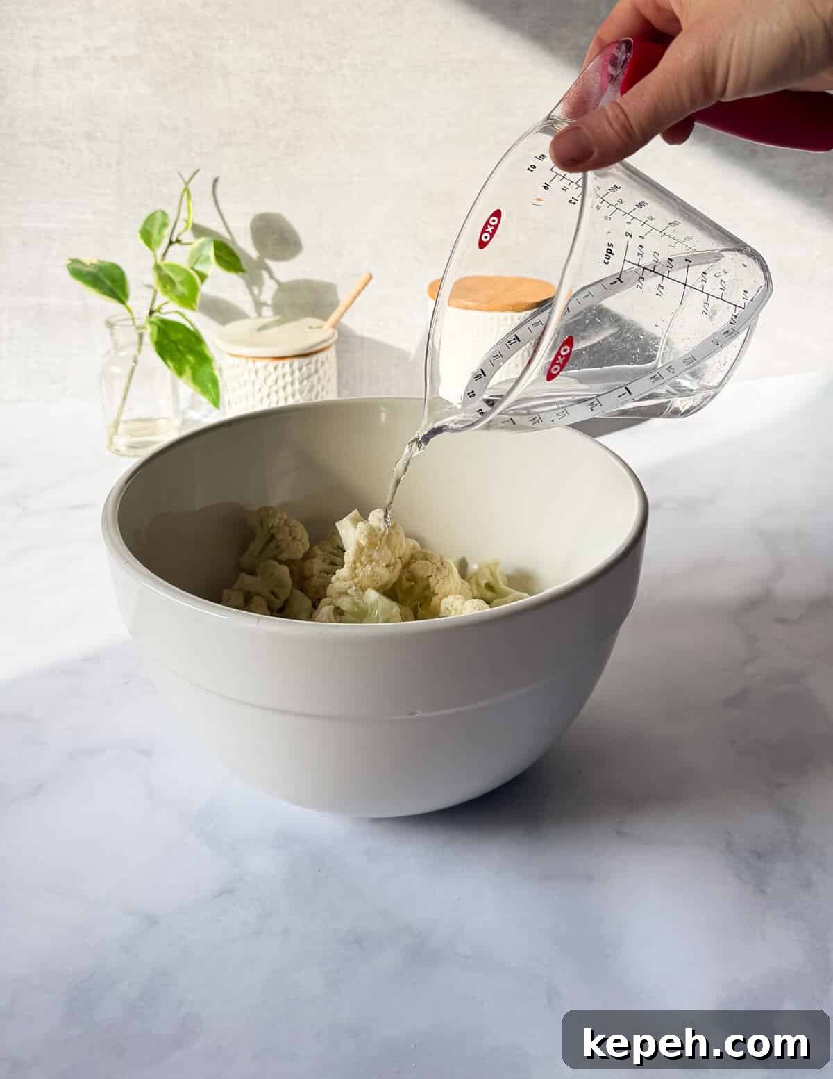Garlic Butter Microwave Cauliflower Recipe for Quick Sides 4 pouring water into a large bowl of cauliflower florets.