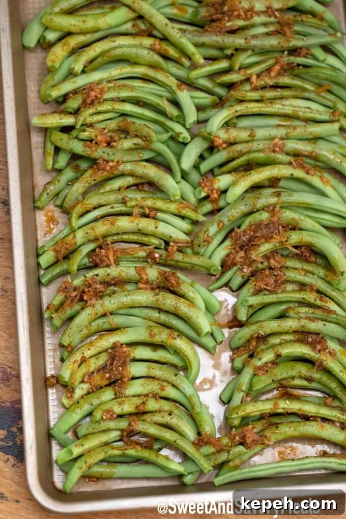 Cheesy Baked Green Beans Casserole with Garlic and Parmesan 4 green beans on a baking sheet topped with garlic and seasoning