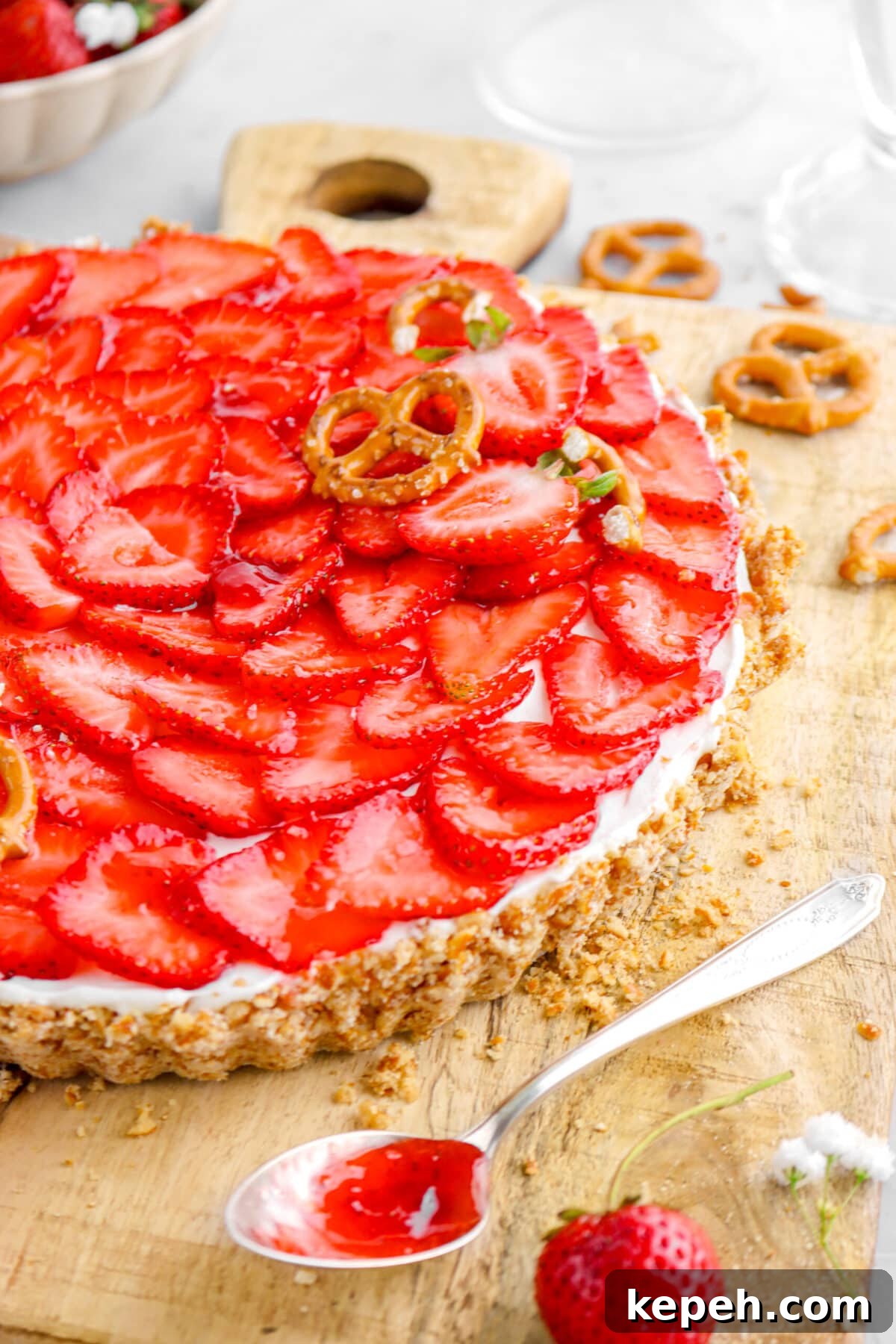 Strawberry Mascarpone Tart with Crunchy Pretzel Crust 3 close up of strawberry tart on wood board with spoon full of jam beside.