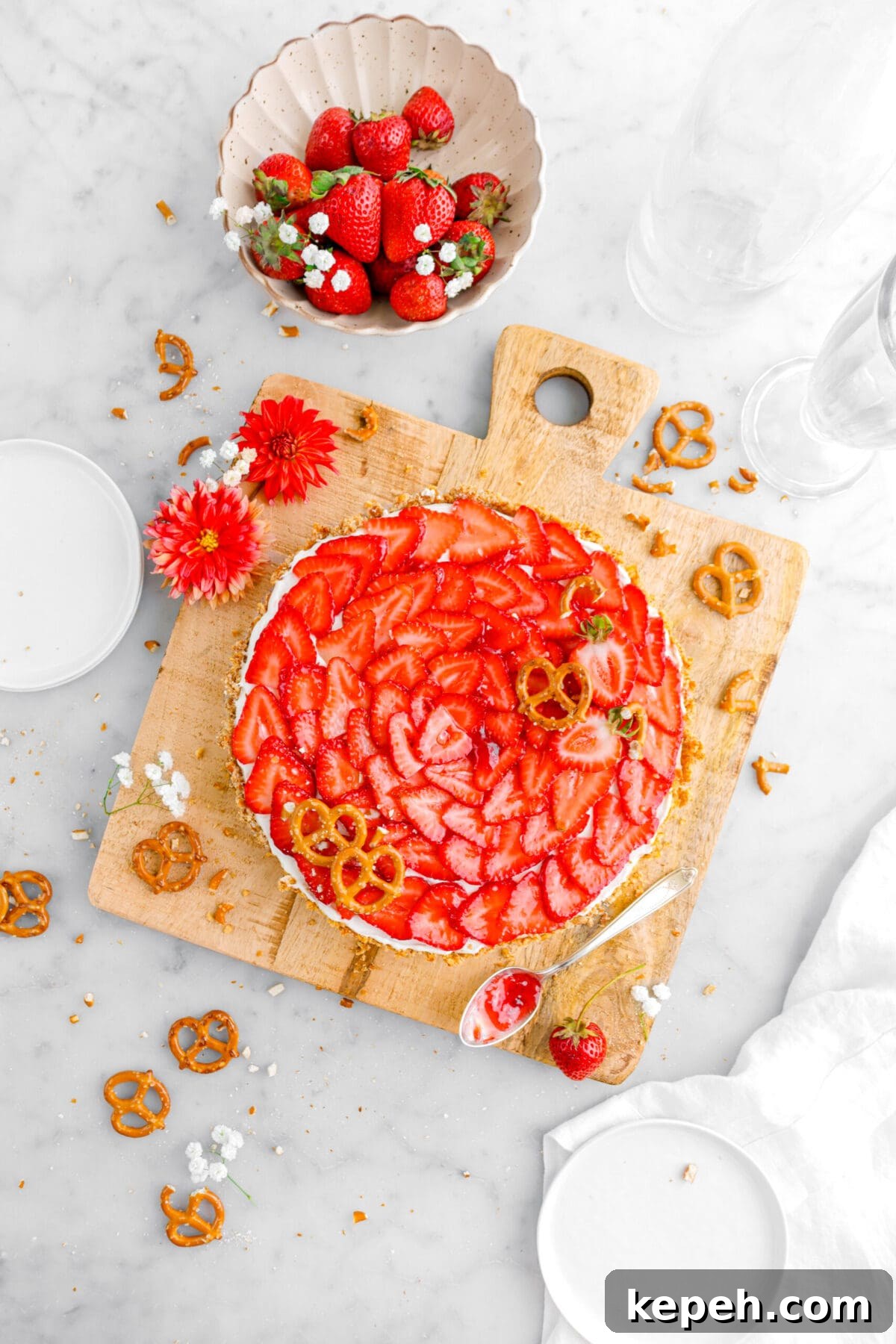 Strawberry Mascarpone Tart with Crunchy Pretzel Crust 4 strawberry tart on square wood board with pretzels on top, more pretzels, strawberries, and flowers around.