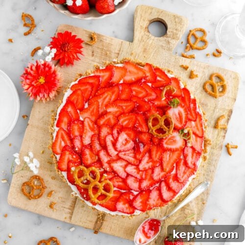 Strawberry Mascarpone Tart with Crunchy Pretzel Crust 21 strawberry tart on square wood serving board with pretzels, strawberries, and flowers around on marble surface and spoon of jam beside tart.
