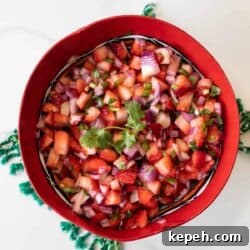 overhead shot of a red bowl filled with strawberry salsa