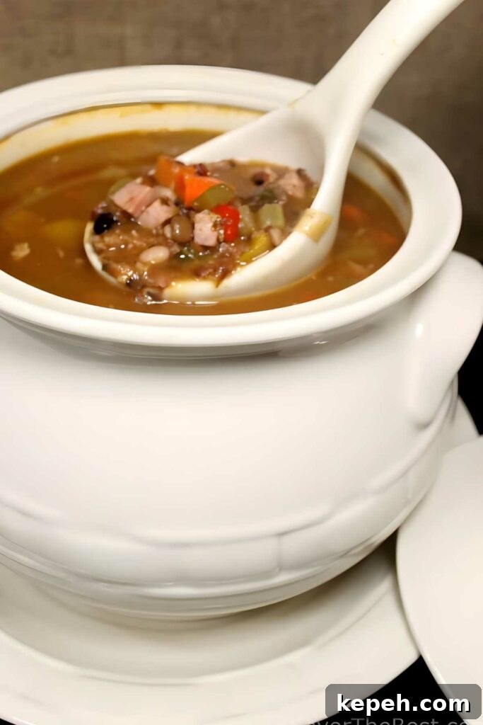 15-Bean Soup Recipe: Hearty, Protein-Packed Comfort Stew 8 White ceramic tureen of soup with beans, vegetables, meat, and ladle.