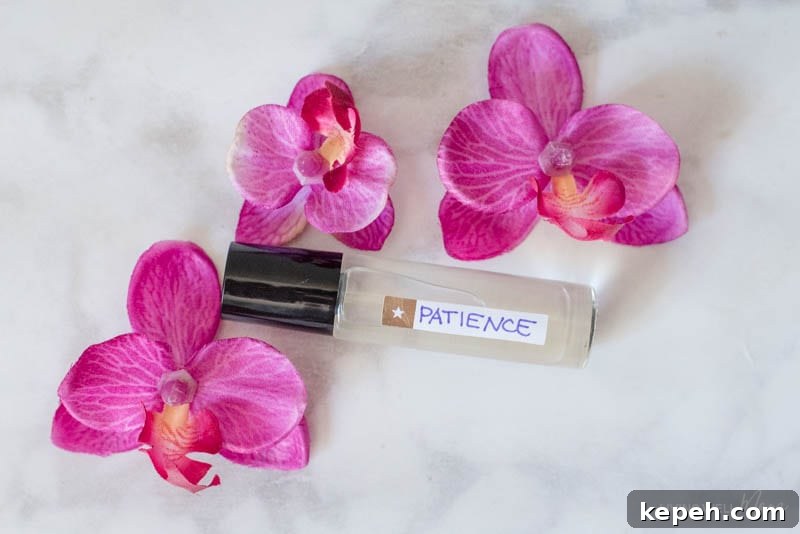 Renewed Patience: DIY Calming Essential Oil Blend for Moms 8 A roller of essential oils for patience, and three pink flowers.