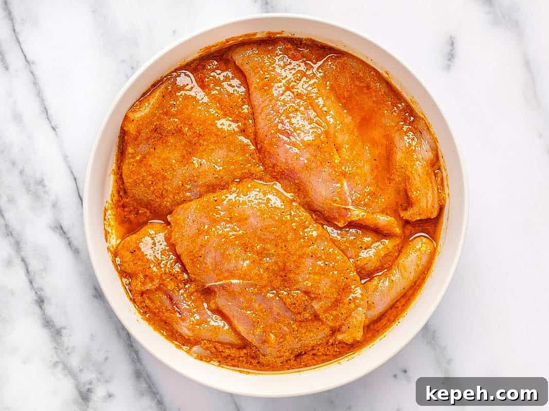 Chicken breast marinating in a large bowl. 