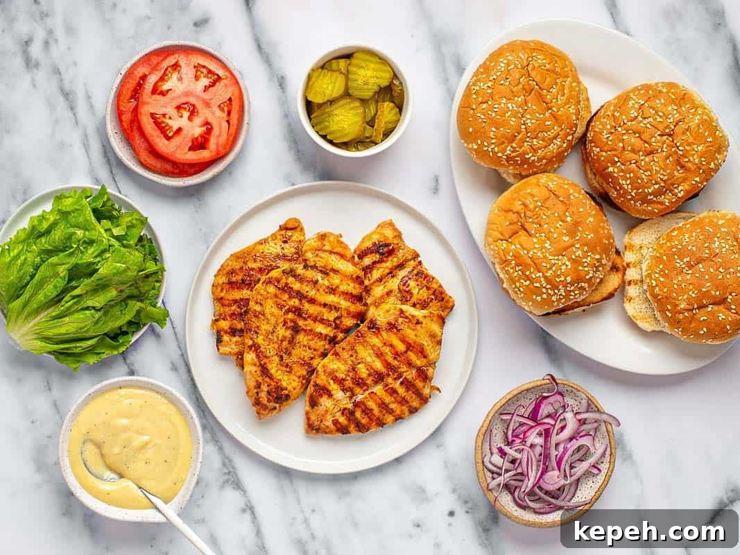 Plates and bowls of ingredients to assemble grilled chicken sandwiches. 