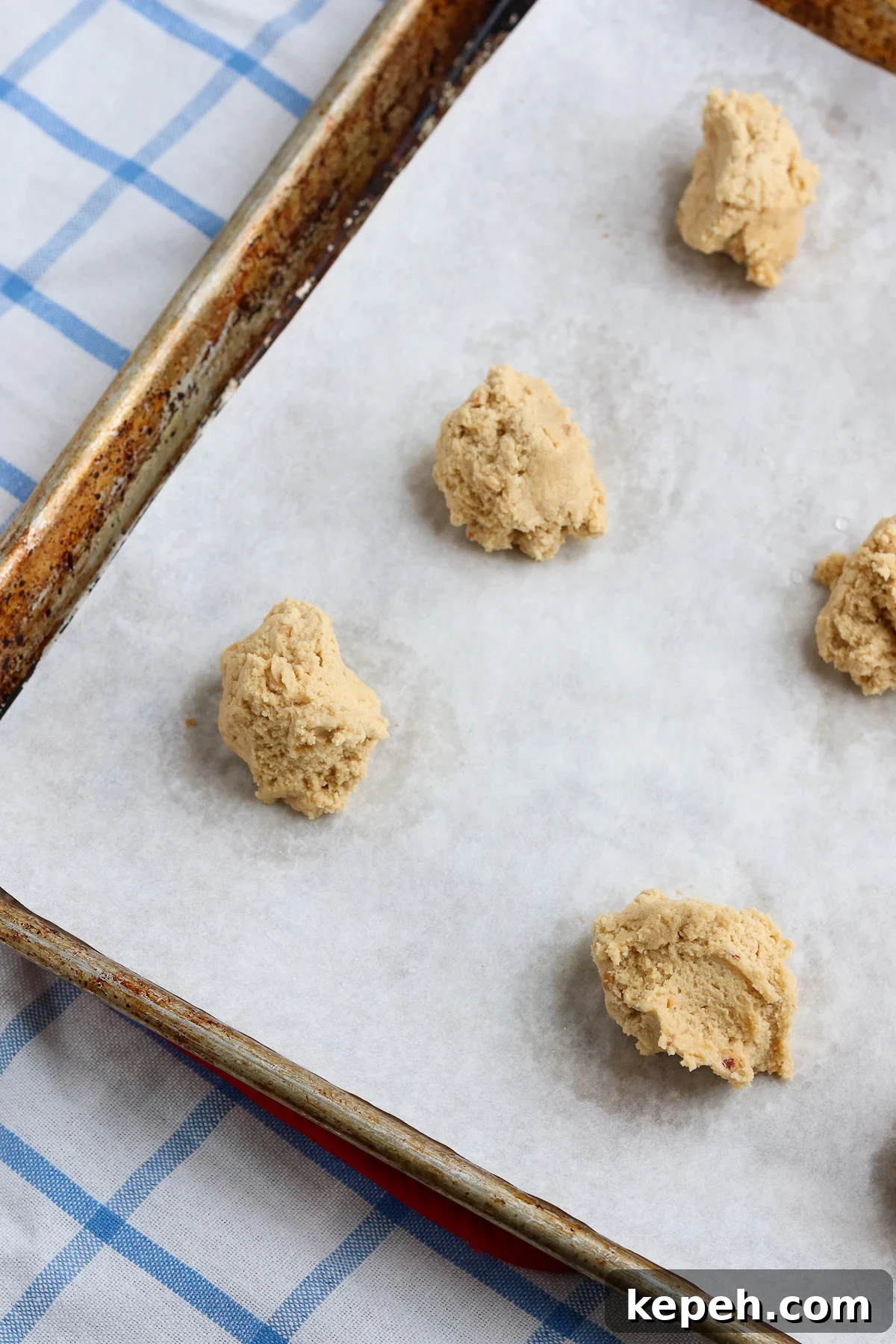 scoops of peanut butter cookie dough on parchment lined baking sheet