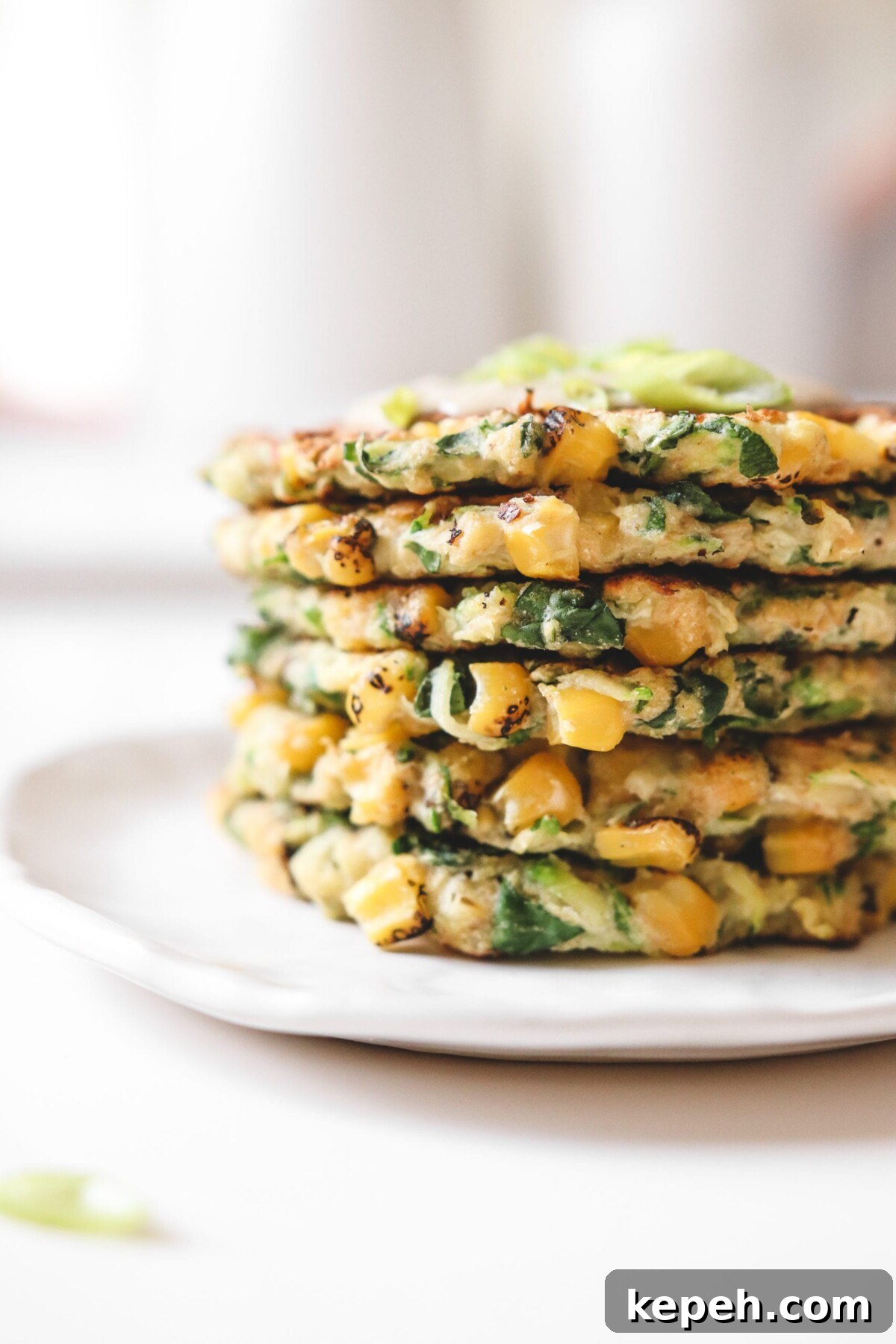 Crispy Gluten-Free Vegan Zucchini Fritters Recipe 2 a stack of vegan zucchini fritters on a white plate
