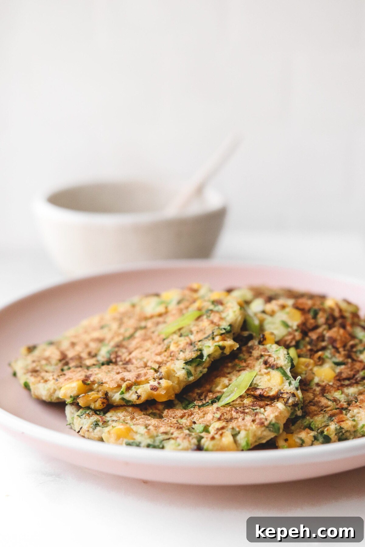 Crispy Gluten-Free Vegan Zucchini Fritters Recipe 3 fritters on a pink plate next to dipping sauce