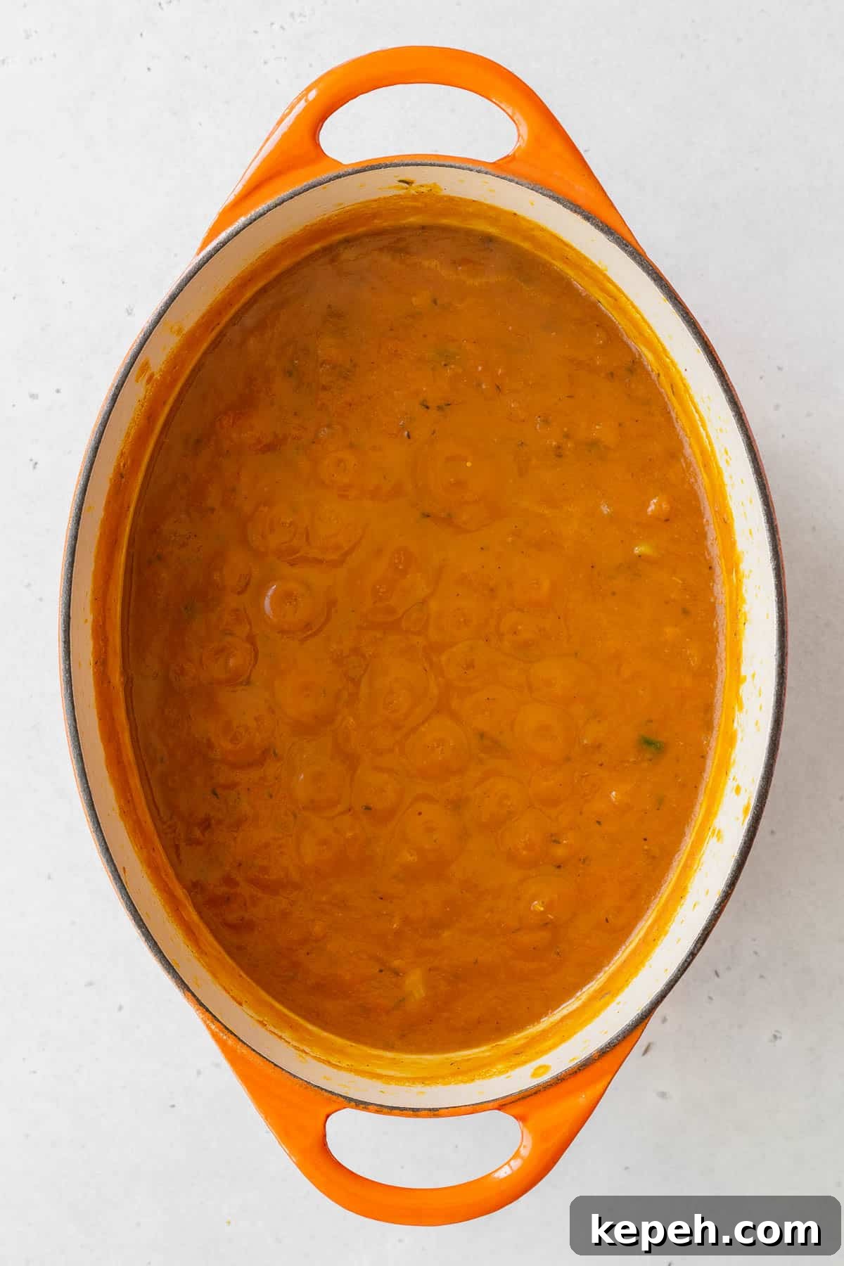 Creamy Plant-Based Pumpkin Soup Recipe for Fall Comfort 7 Pumpkin puree, veggie broth, and garlic powder added to the pot with the onions and spices.