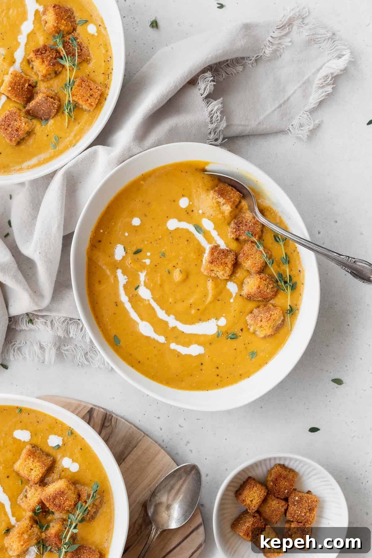 Creamy Plant-Based Pumpkin Soup Recipe for Fall Comfort 10 Overhead shot of a bowl of vegan pumpkin bisque soup garnished with fresh thyme, cornbread croutons, and a drizzle of vegan cream.