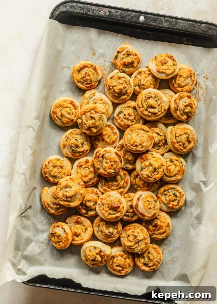 A sheet pan of baked jalapeño popper pinwheels on a tan counter.