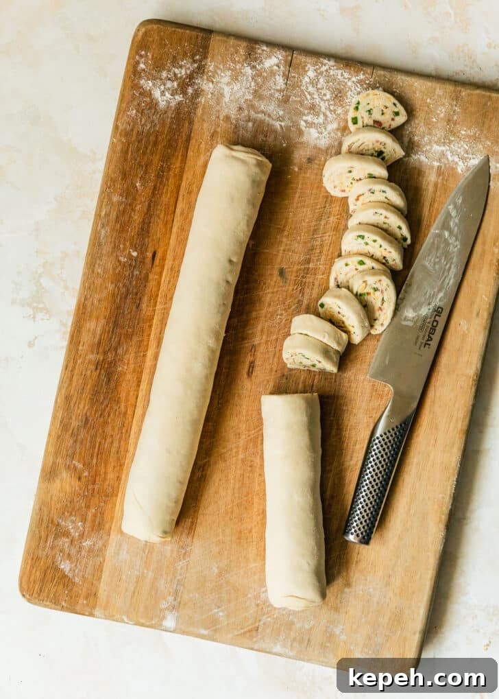 Sliced jalapeño popper pinwheels on a wood board.