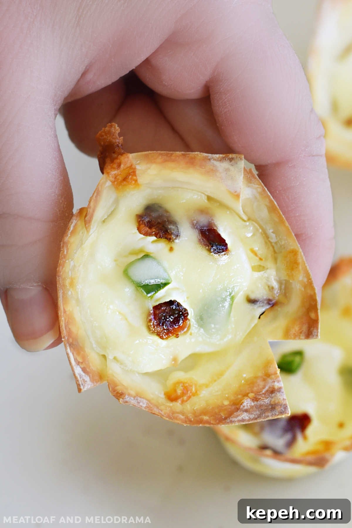 Bacon Jalapeño Popper Wonton Cups — Crispy Bite-Sized Appetizers 7 hand holding mini jalapeno popper wonton cup with bacon