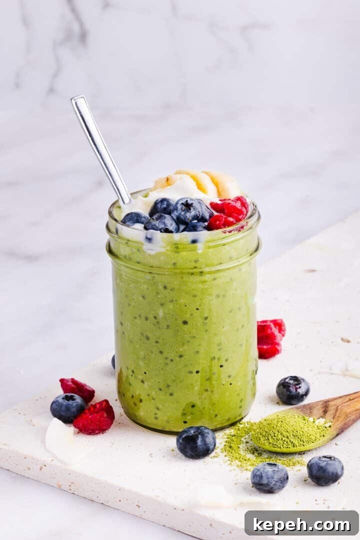 A glass jar filled with matcha overnight oats, topped with fresh berries and banana slices