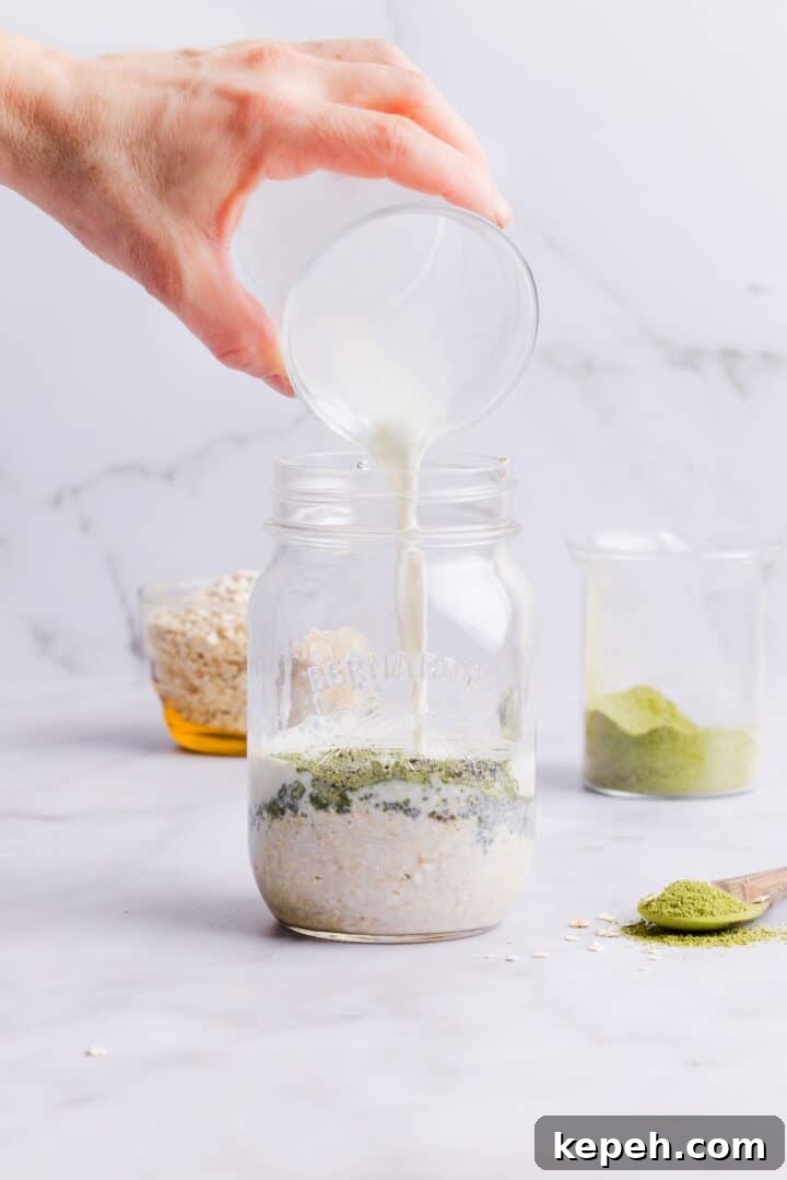 Milk being poured into glass mason jar with matcha overnight oats