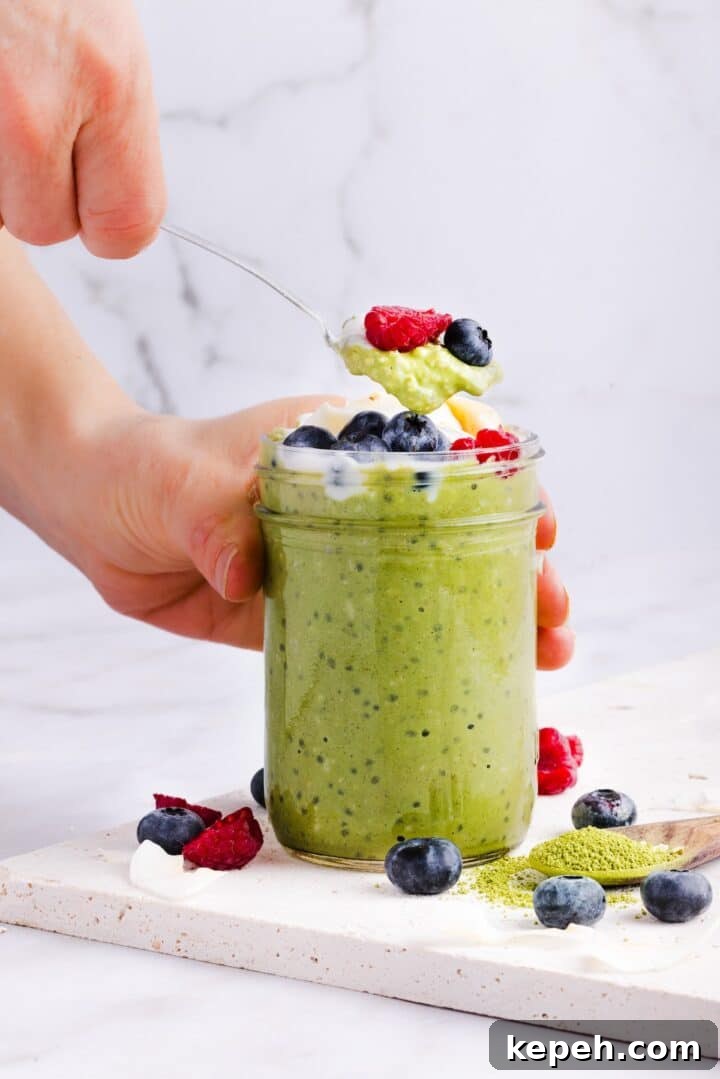 Woman's hand lifting a spoonful of matcha overnight oats
