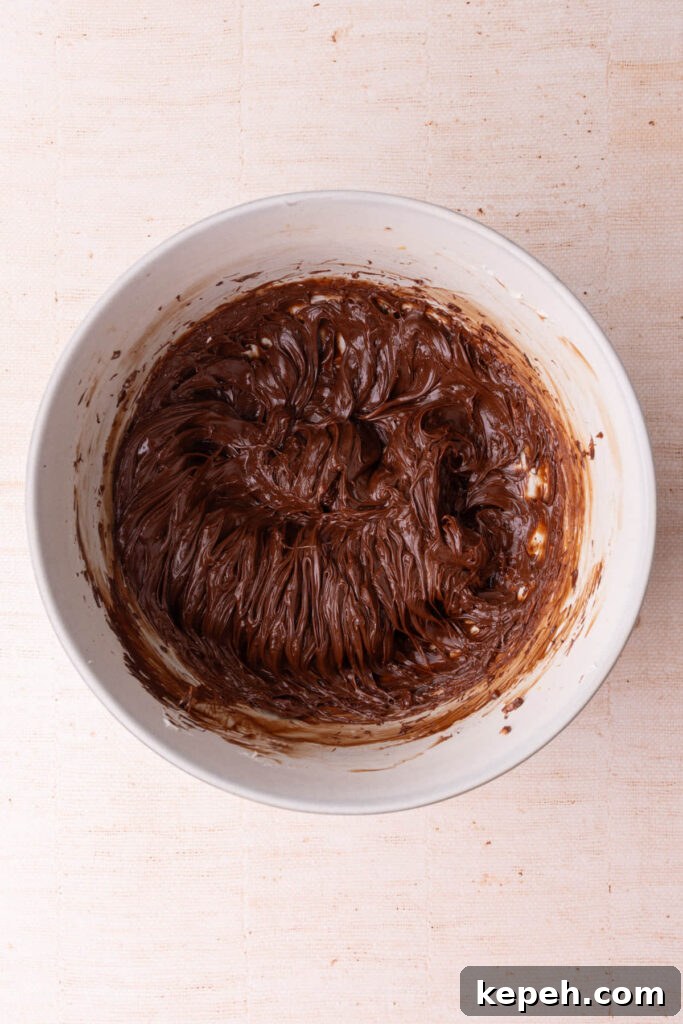 Melted chocolate whipped into softened butter in a large mixing bowl. 
