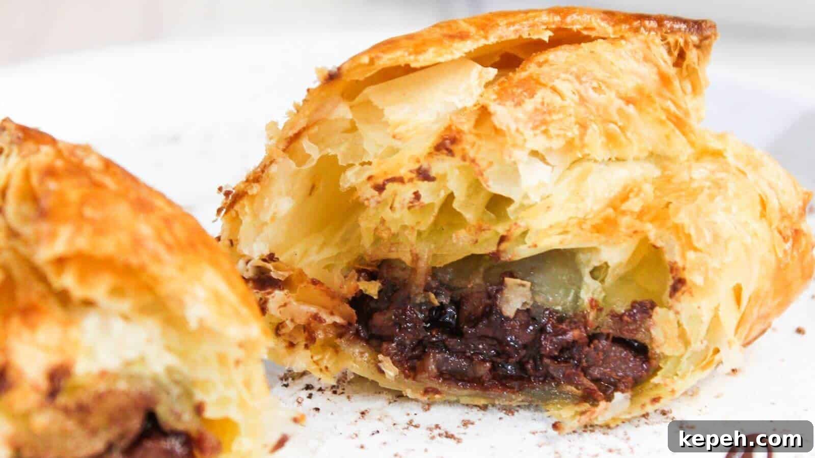 Close-up of a flaky pastry cut open to reveal a filling of chocolate, with a visible crispy golden crust.