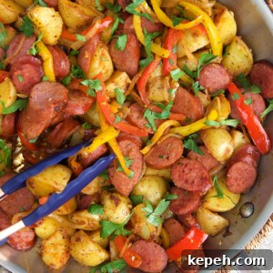 Kielbasa and Potatoes in a skillet being sautéed.