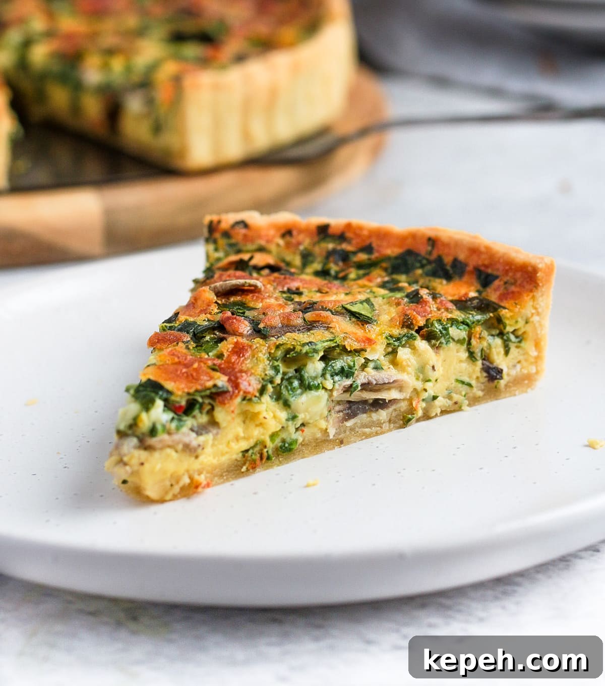One slice of quiche on a white plate