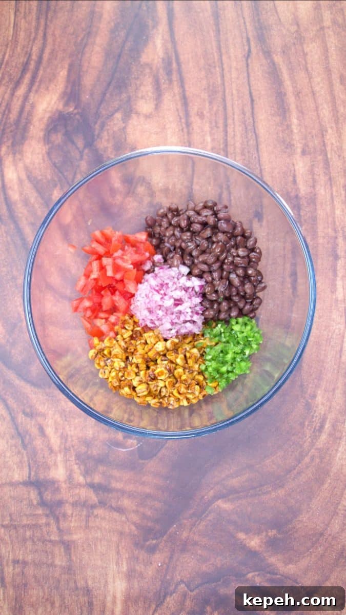 Fresh Avocado Salsa with Corn & Black Beans — Zesty Summer Dip 6 A mixing bowl filled with corn, black beans, jalapeno, tomatoes and red onion to make avocado salsa with corn and black beans - Hostess At Heart