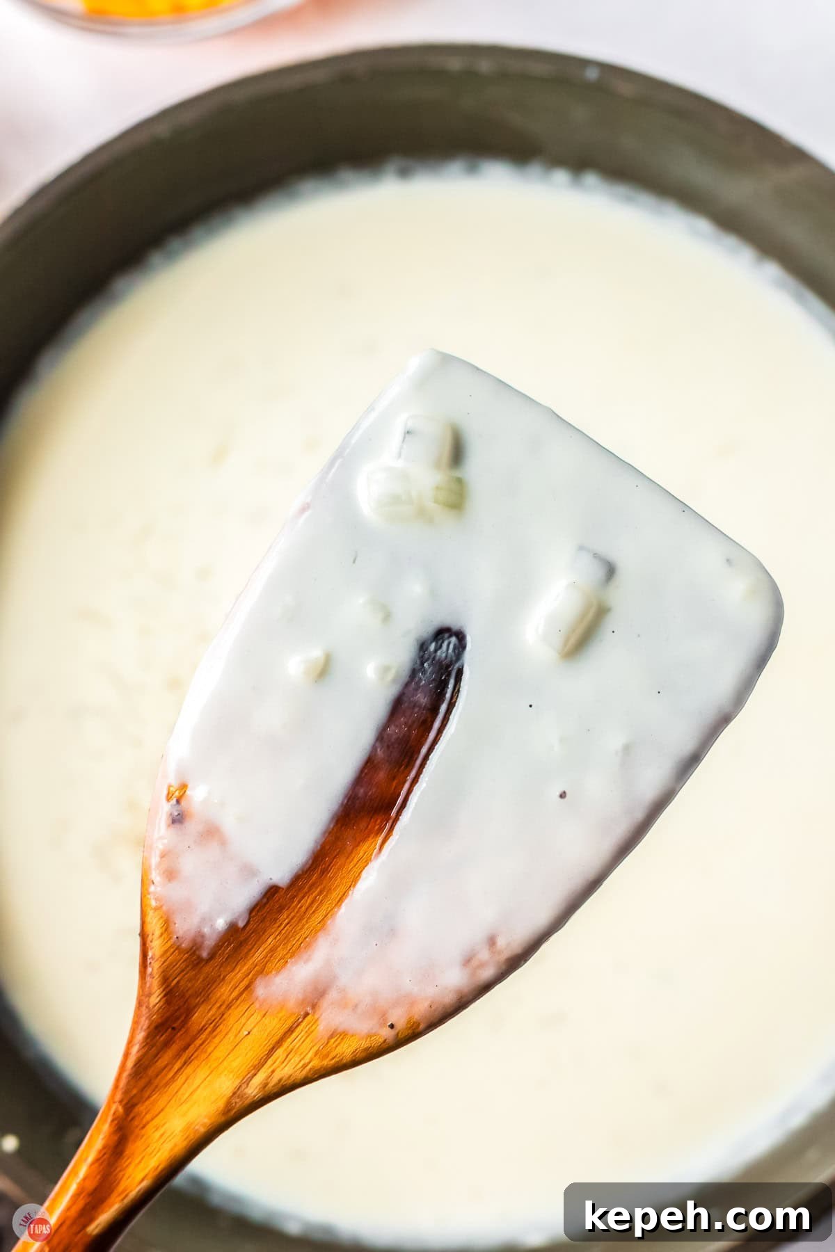 Classic Green Pea Casserole Recipe for Family Dinners 11 close up of cream sauce on a wood spoon with a finger swipe missing out of it