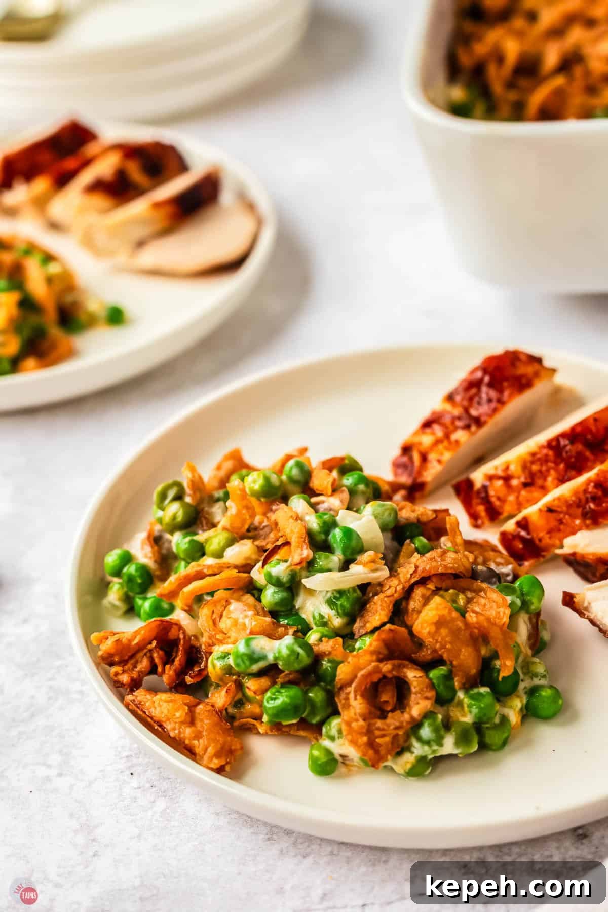 Classic Green Pea Casserole Recipe for Family Dinners 8 white plate with sliced chicken breast and green peas next to it