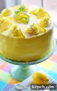 Lemon layer cake iced with yellow buttercream on a turquoise cake pedestal and pastel checked napkin.