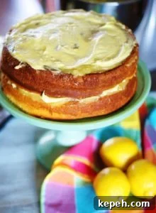 2 layers of lemon cake uniced on a turquoise cake pedestal. Between the layers are lemon curd and lemon buttercream.