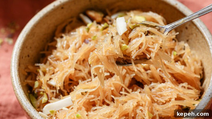 Holding a spoonful of Sukhi Seviyan garnished with slivered almonds and chopped pistachios.