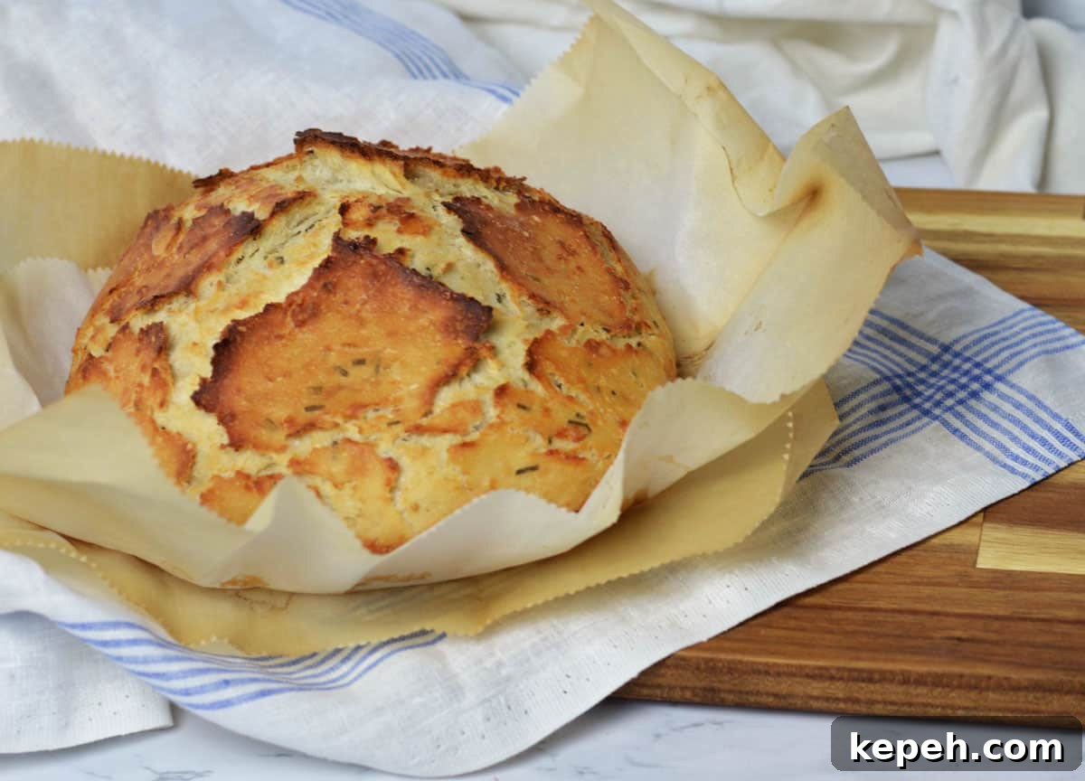 Savory Herb and Cheese Loaf Recipe for Homemade Bread 2 round loaf of herb and cheese bread sitting atop linen dish towels and parchment paper.
