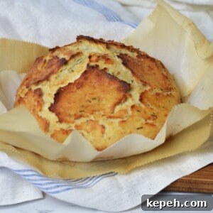 Savory Herb and Cheese Loaf Recipe for Homemade Bread 9 crisp loaf of herb and cheese bread laying on layers of parchment paper and linen cloths.