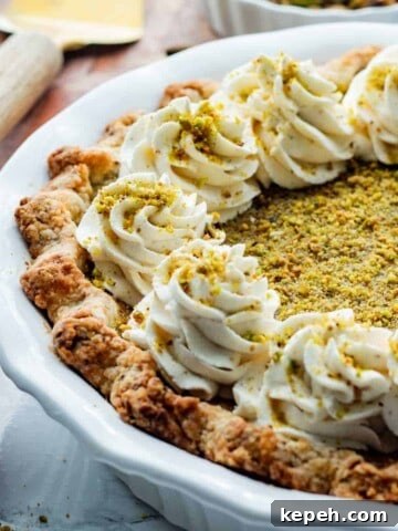 Baked Pistachio pie in white pie dish with whipped cream on top.