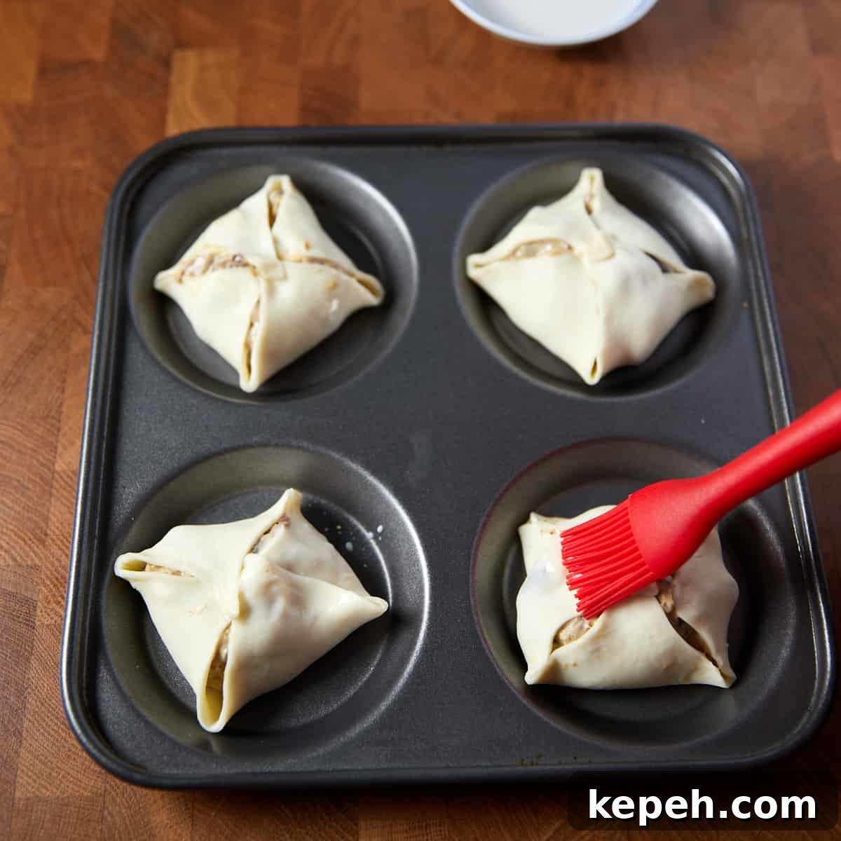 Photo showing plant-based milk being brushed over the top of the vegan mushroom hand pies before baking.